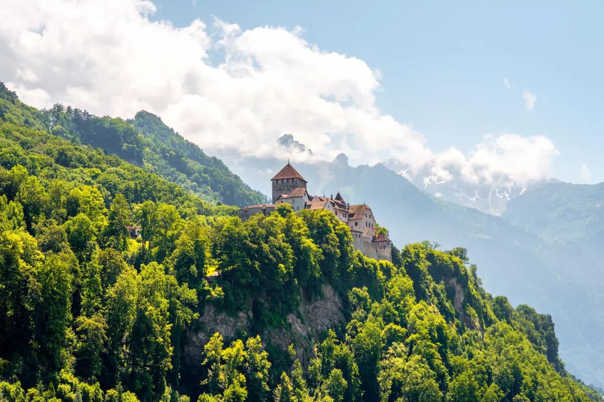 Ein Bergpanorama mit dem Schloss Vaduz in der Hauptstadt von Liechtenstein an einem sonnigen Tag.